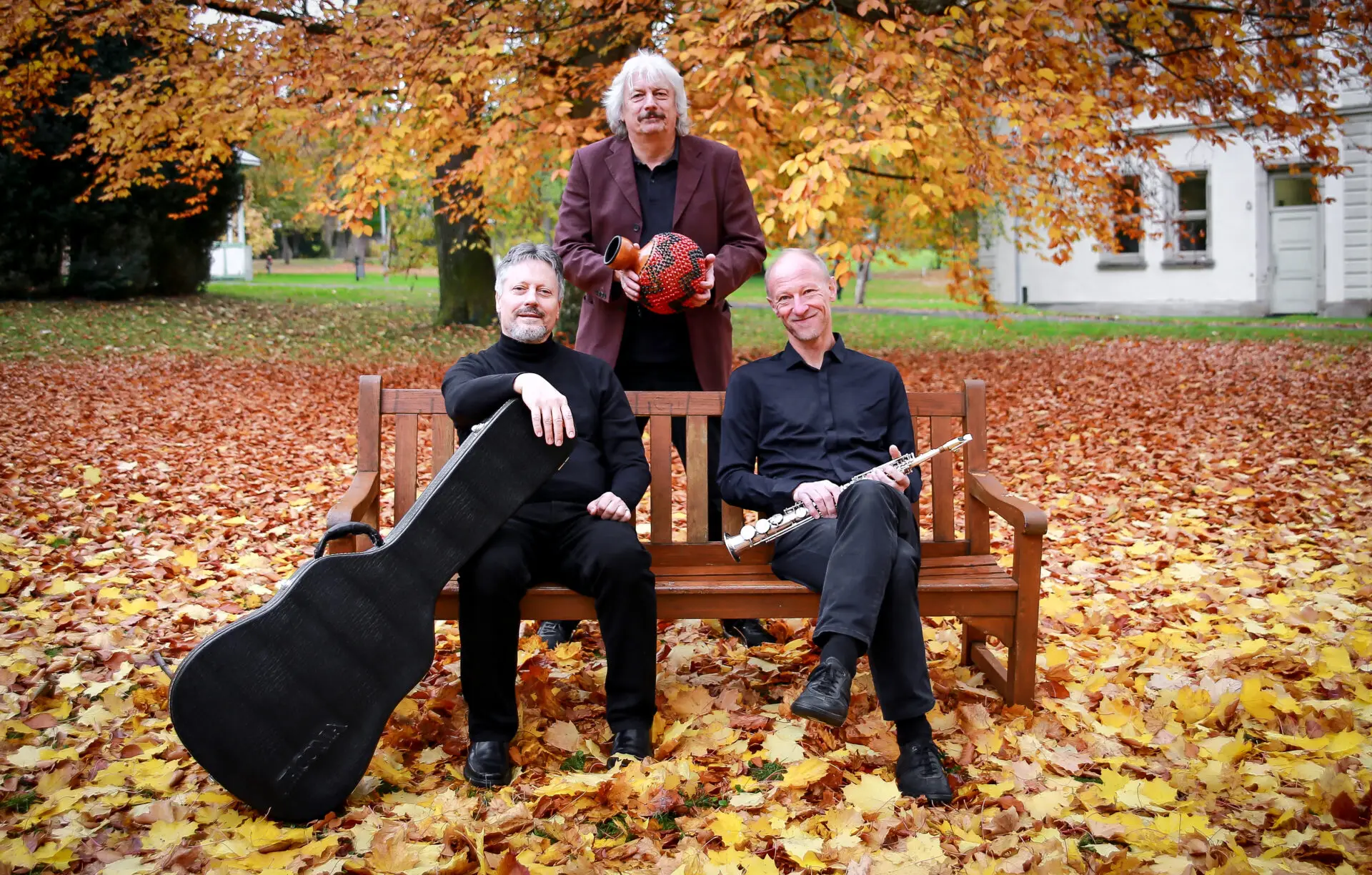 Musiktrio Zwischenwelten, klassische Musik, auf Bank im Herbstlaub sitzend